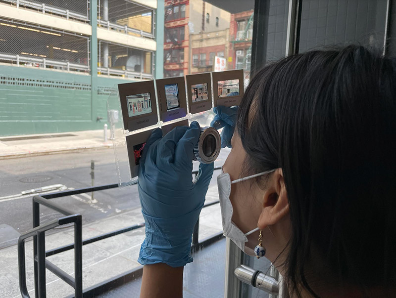 Denise Lu uses a photo loupe to inspect archival slides for evidence of historic street signs.